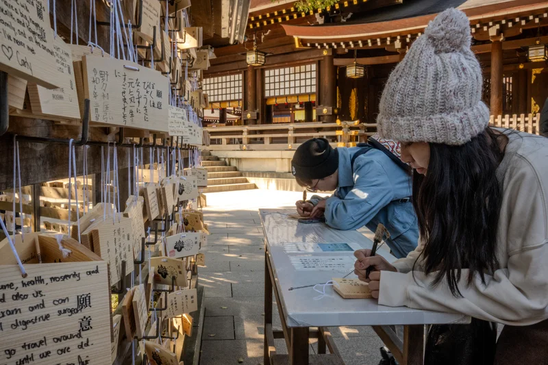Woman writing on Ema Plaque